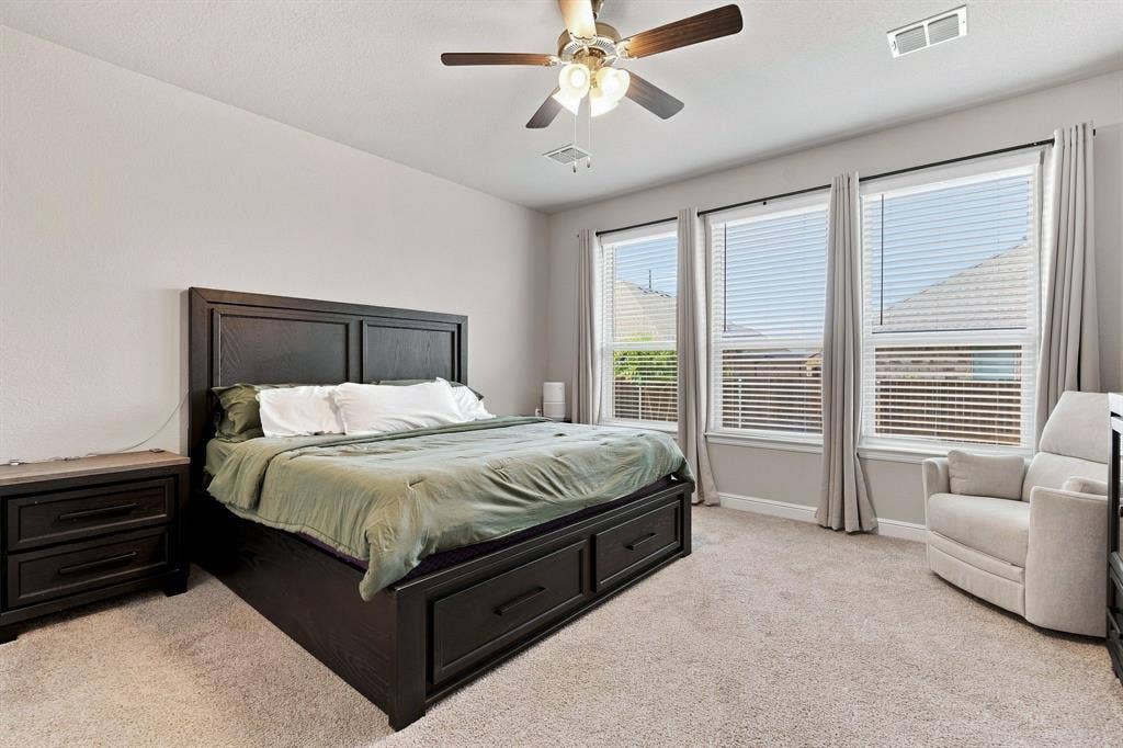 Light-toned walls, recessed ceiling fan with integrated lighting, three large windows with blinds, and neutral-toned carpeting