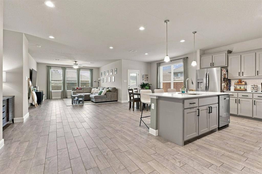 Open-concept living space featuring wood-finish flooring, recessed lighting, a ceiling fan, and large windows with blinds