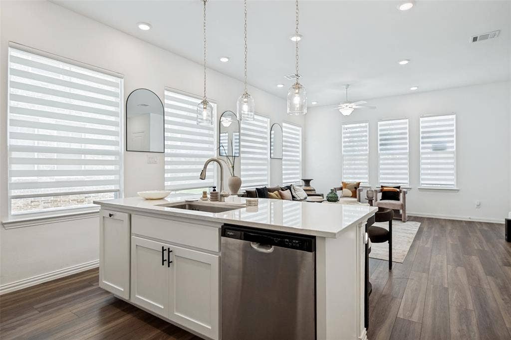 7536 Laburnam Road, Dallas, TX 75228 Kitchen island with a built-in sink, stainless steel dishwasher, and white cabinetry with matte black hardware
