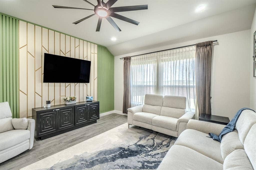 Accent wall with geometric and vertical paneling, dark wood-finish media console, recessed lighting, and a ceiling fan with integrated lighting