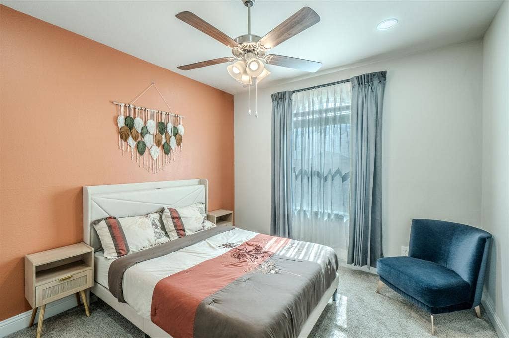 Recessed lighting, ceiling fan with light fixture, window with drapes, and a textured accent wall