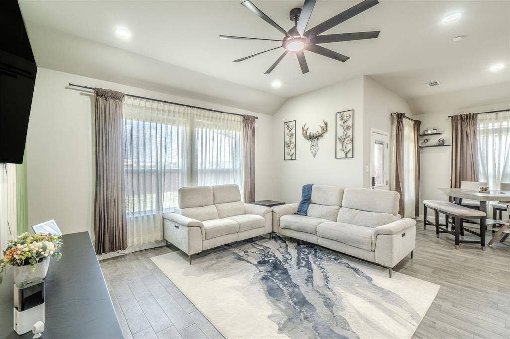 Vaulted ceiling with a contemporary ceiling fan, recessed lighting, wood-finish flooring, and expansive windows