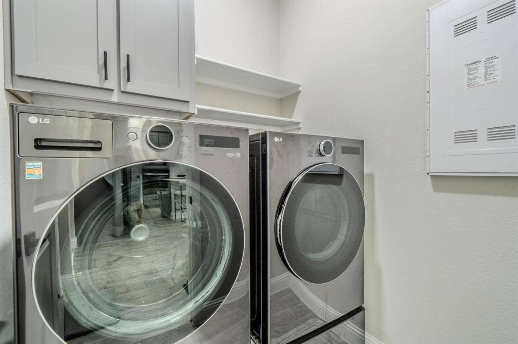 Laundry area featuring gray cabinetry, integrated shelving, and wood-finish flooring