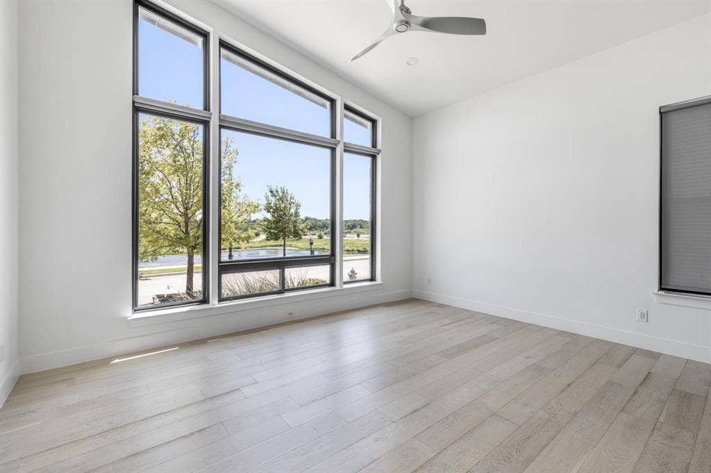 1321 Black Walnut Lane, Arlington, TX 76005 Bright corner room showcasing expansive multi-pane windows with black aluminum frames, light wood-finish flooring, and ceiling fan