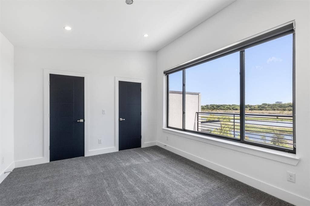 1321 Black Walnut Lane, Arlington, TX 76005 Bright corner bedroom featuring expansive multi-pane windows with black aluminum frames, panoramic countryside outlook, recessed ceiling lighting, neutral wall finishes, and neutral-tone carpeting throughout
