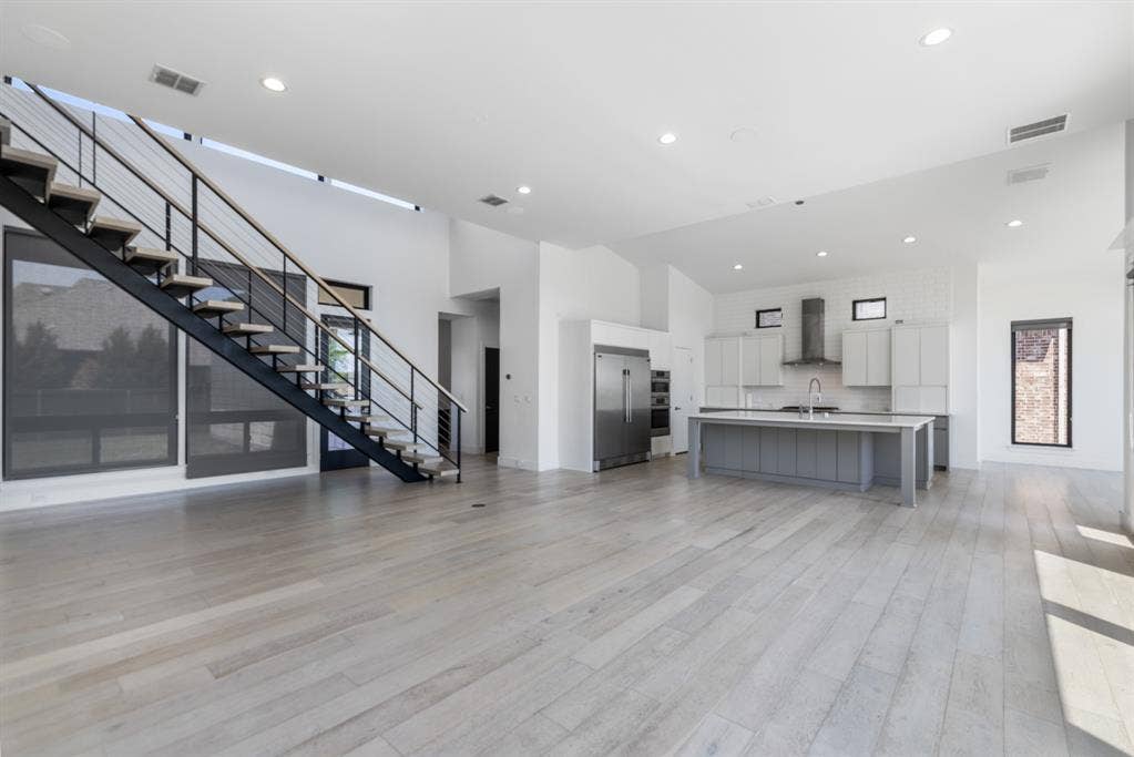 1321 Black Walnut Lane, Arlington, TX 76005 Open-concept living space featuring light wood-finish flooring, recessed ceiling lighting, and floor-to-ceiling windows with metal railings