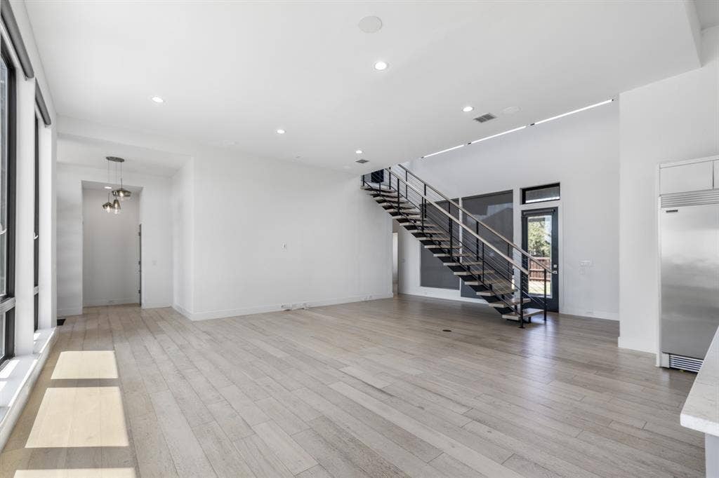 1321 Black Walnut Lane, Arlington, TX 76005 Spacious open-concept interior featuring light wood-finish flooring, high ceilings, recessed lighting, and a modern open-tread staircase with metal railings