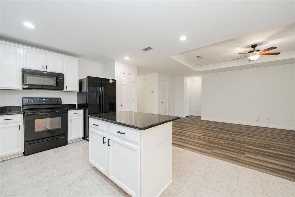 122 Feverbush Drive, Fate, TX 75189 Kitchen featuring black appliances, ornamental molding, white cabinets, ceiling fan, and a raised ceiling