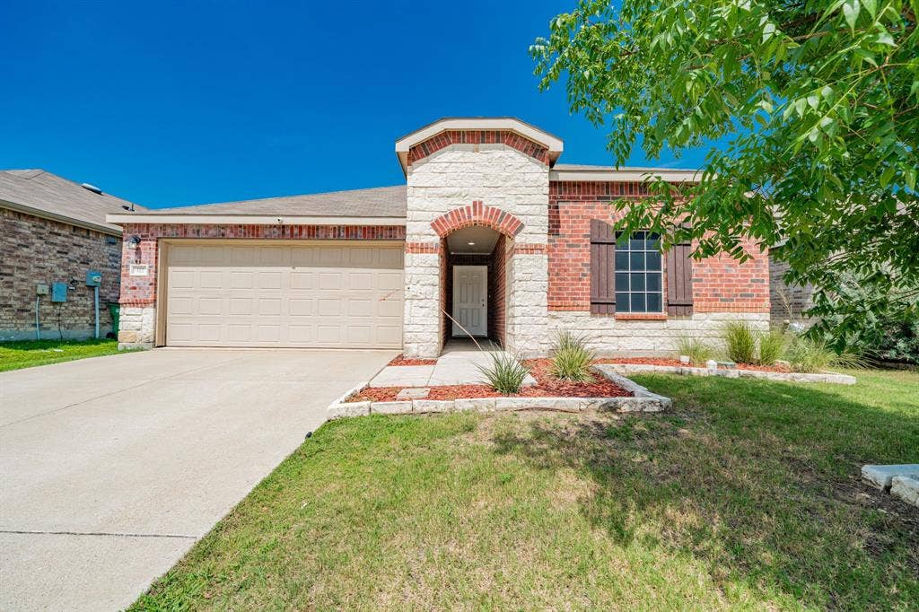 122 Feverbush Drive, Fate, TX 75189 View of front of house featuring an attached garage, stone siding, concrete driveway, a front lawn, and brick siding