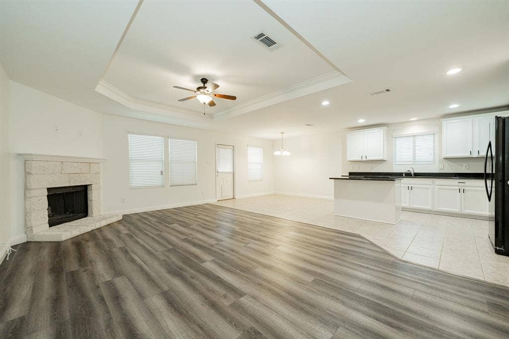 122 Feverbush Drive, Fate, TX 75189 Unfurnished living room featuring a ceiling fan, a raised ceiling, crown molding, a chandelier, and light wood finished floors