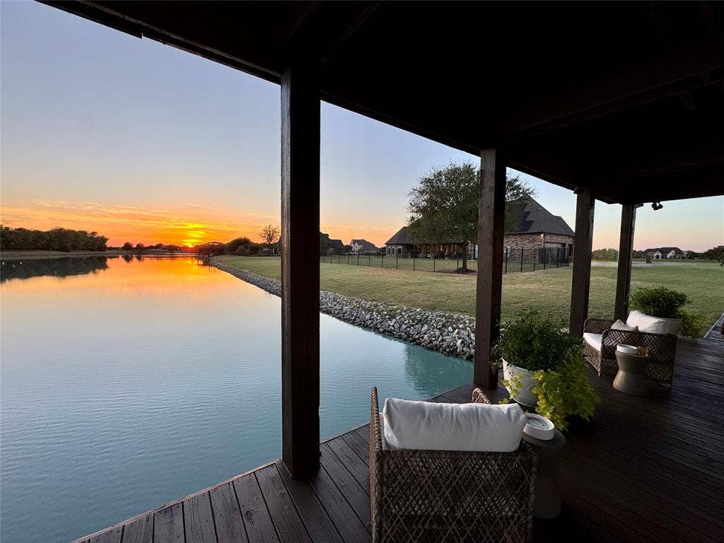 623 Calm Water Cove, Princeton, TX 75407 Covered outdoor patio with a dark wood-finish deck, overlooking a serene body of water, and a landscaped lawn