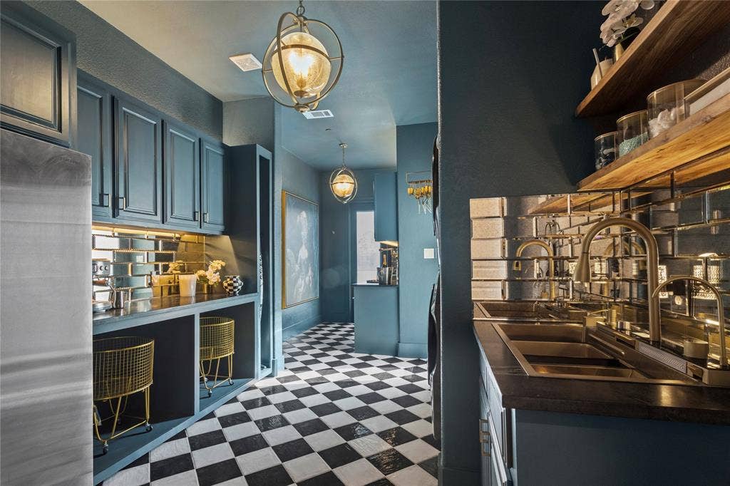 623 Calm Water Cove, Princeton, TX 75407 Checkerboard tile flooring, custom teal cabinetry, mirrored subway tile backsplash, dual stainless steel sinks, and spherical pendant lighting
