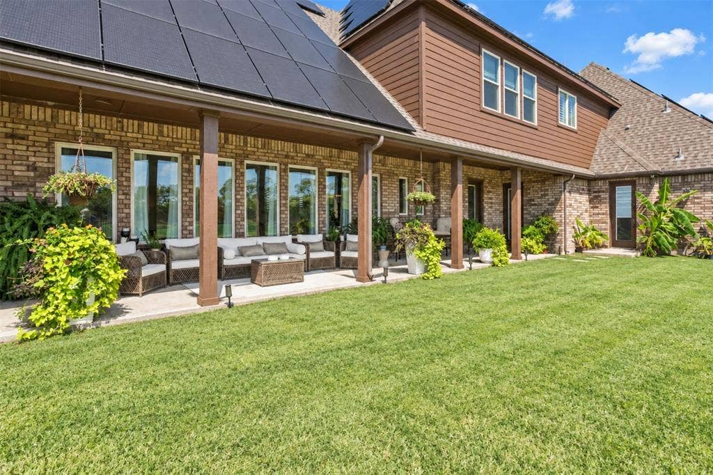 623 Calm Water Cove, Princeton, TX 75407 Expansive green lawn with a covered patio featuring wood-finish columns and multiple windows