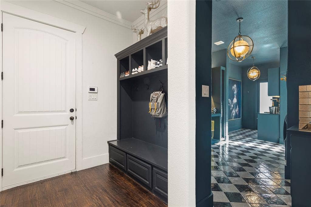 623 Calm Water Cove, Princeton, TX 75407 Built-in hall tree with integrated storage and seating, hardwood flooring, arched panel door, and checkered tile flooring in the hallway
