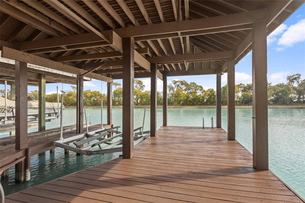 623 Calm Water Cove, Princeton, TX 75407 Covered boat dock featuring durable wood decking, exposed wood rafters, and a built-in boat lift