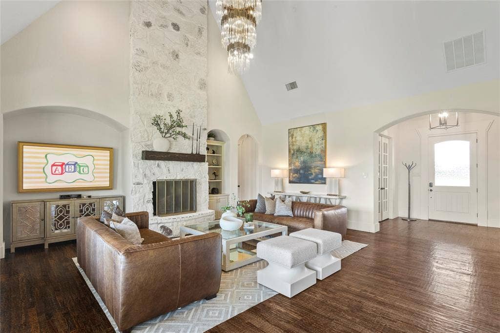 623 Calm Water Cove, Princeton, TX 75407 Vaulted ceiling, stone fireplace with a wood mantel, dark wood-finish flooring, arched doorways, and a contemporary chandelier