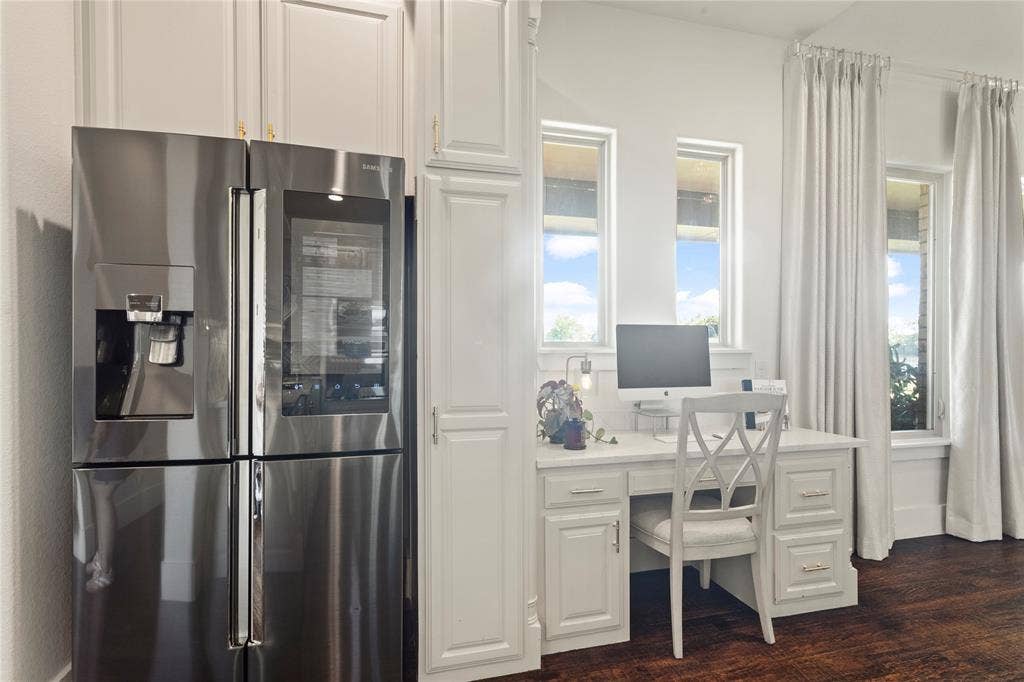 623 Calm Water Cove, Princeton, TX 75407 Built-in desk with paneled cabinetry, stainless steel French door refrigerator, and multiple windows with drapery rods