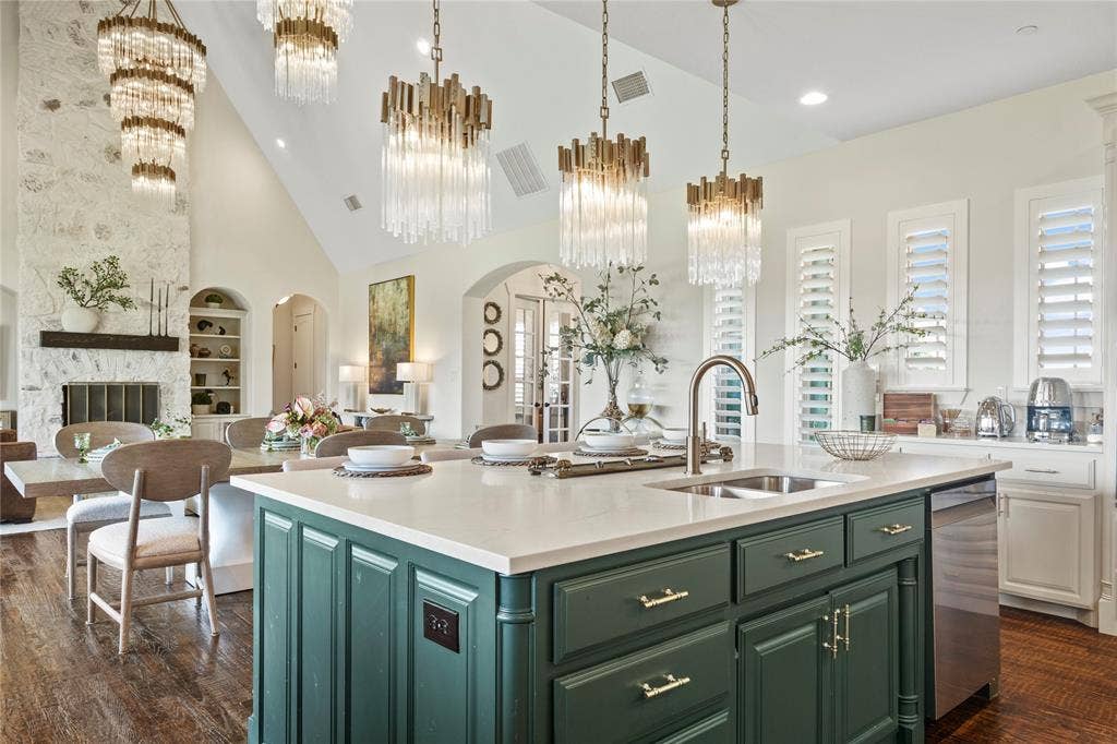 623 Calm Water Cove, Princeton, TX 75407 Vaulted ceiling, stone fireplace with wood mantel, large kitchen island with integrated sink, built-in shelving, and wood-finish flooring
