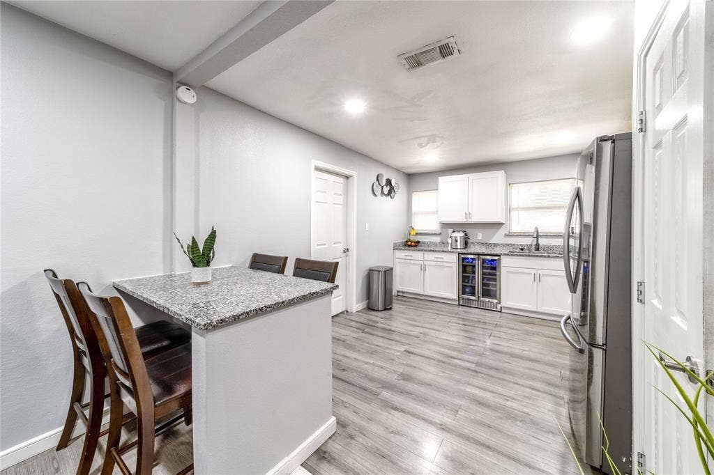 726 Royal Crest, Mesquite, TX 75149 Kitchen with freestanding refrigerator, light stone counters, a breakfast bar, white cabinets, and wine cooler