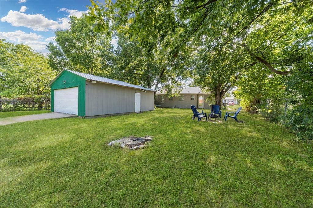 726 Royal Crest, Mesquite, TX 75149 View of yard featuring an outbuilding, a detached garage, an outdoor fire pit, and view of wooded area