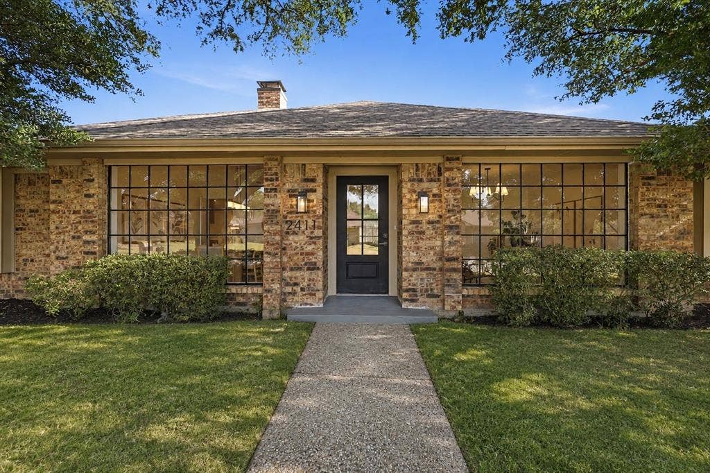 2411 Aspen Street, Richardson, TX 75082 Brick facade with extensive grid-pattern windows, a black entry door, and a shingle roof