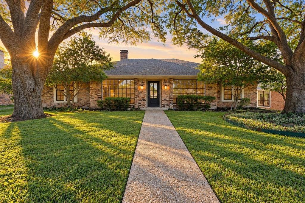 2411 Aspen Street, Richardson, TX 75082 Brick exterior with a dark-paneled front door, an extensive front lawn, mature trees, and a concrete walkway