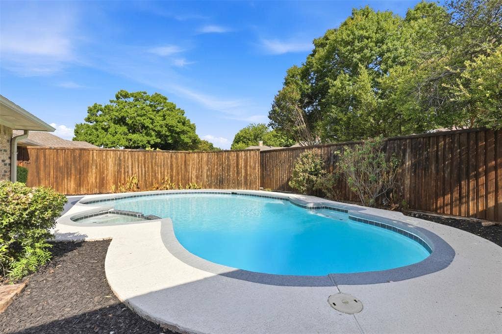 2411 Aspen Street, Richardson, TX 75082 Resort-style pool with integrated spa, concrete decking, and wood privacy fencing