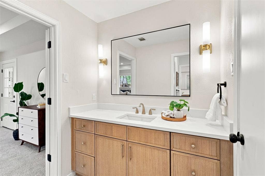 2411 Aspen Street, Richardson, TX 75082 Wood-finish vanity with a white countertop and undermount sink