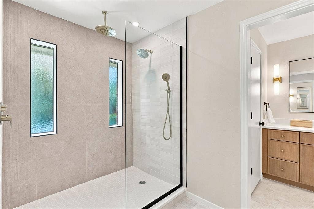 2411 Aspen Street, Richardson, TX 75082 Glass-enclosed shower with a rainfall showerhead, handheld shower, and vertical accent windows