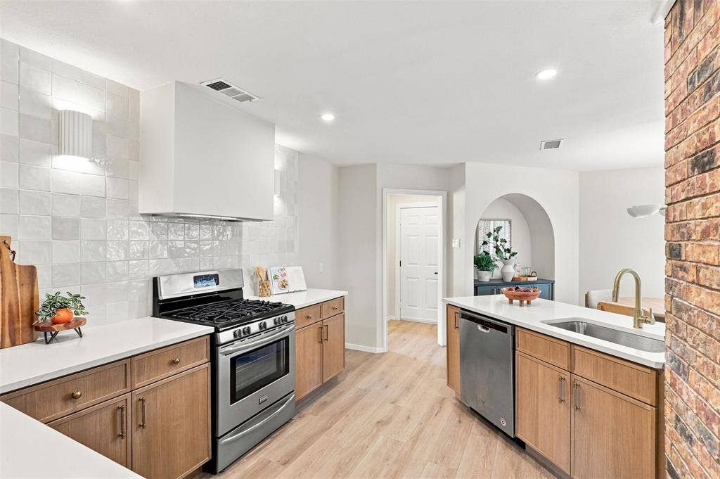 2411 Aspen Street, Richardson, TX 75082 Kitchen featuring stainless steel appliances, wood-finish cabinetry, white countertops, and a full tile backsplash
