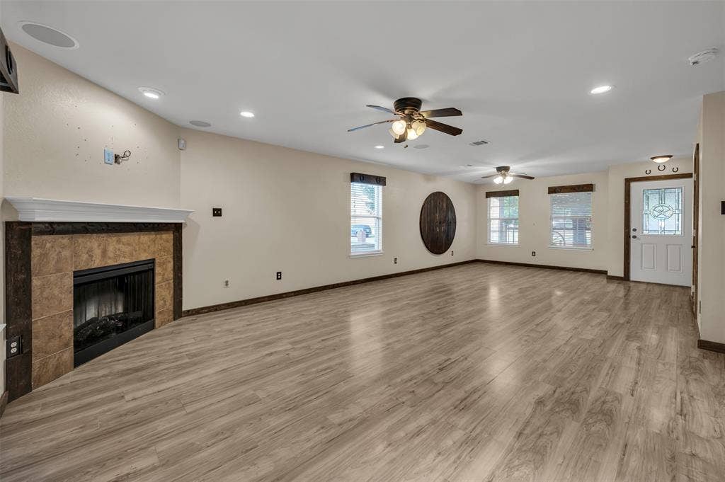 9017 Graywolf Ridge Trail, Fort Worth, TX 76244 Unfurnished living room with wood-type flooring, ceiling fan, and a tile fireplace