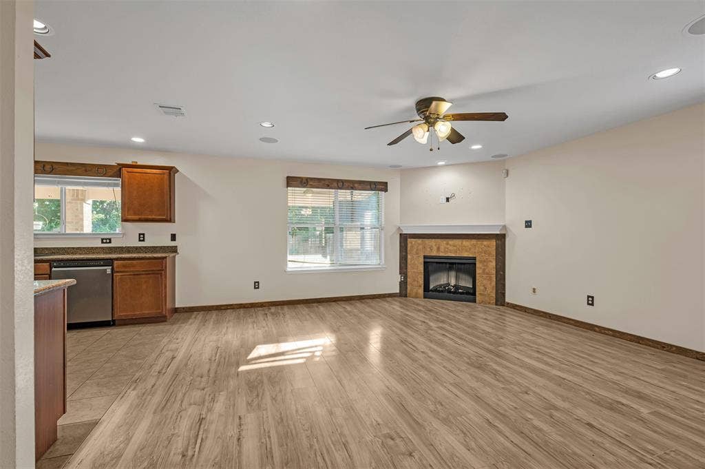 9017 Graywolf Ridge Trail, Fort Worth, TX 76244 Unfurnished living room with ceiling fan, a tiled fireplace, and light hardwood / wood-style floors