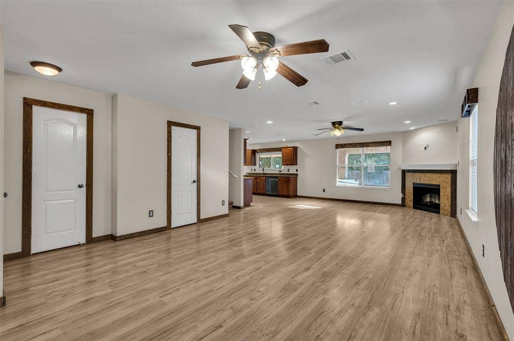 9017 Graywolf Ridge Trail, Fort Worth, TX 76244 Unfurnished living room featuring ceiling fan, a tile fireplace, and light wood-type flooring