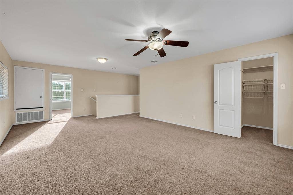 9017 Graywolf Ridge Trail, Fort Worth, TX 76244 Unfurnished bedroom featuring a closet, ceiling fan, a walk in closet, and light colored carpet