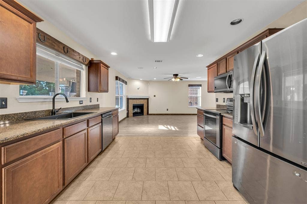 9017 Graywolf Ridge Trail, Fort Worth, TX 76244 Kitchen featuring light tile flooring, stainless steel appliances, ceiling fan, sink, and a tile fireplace