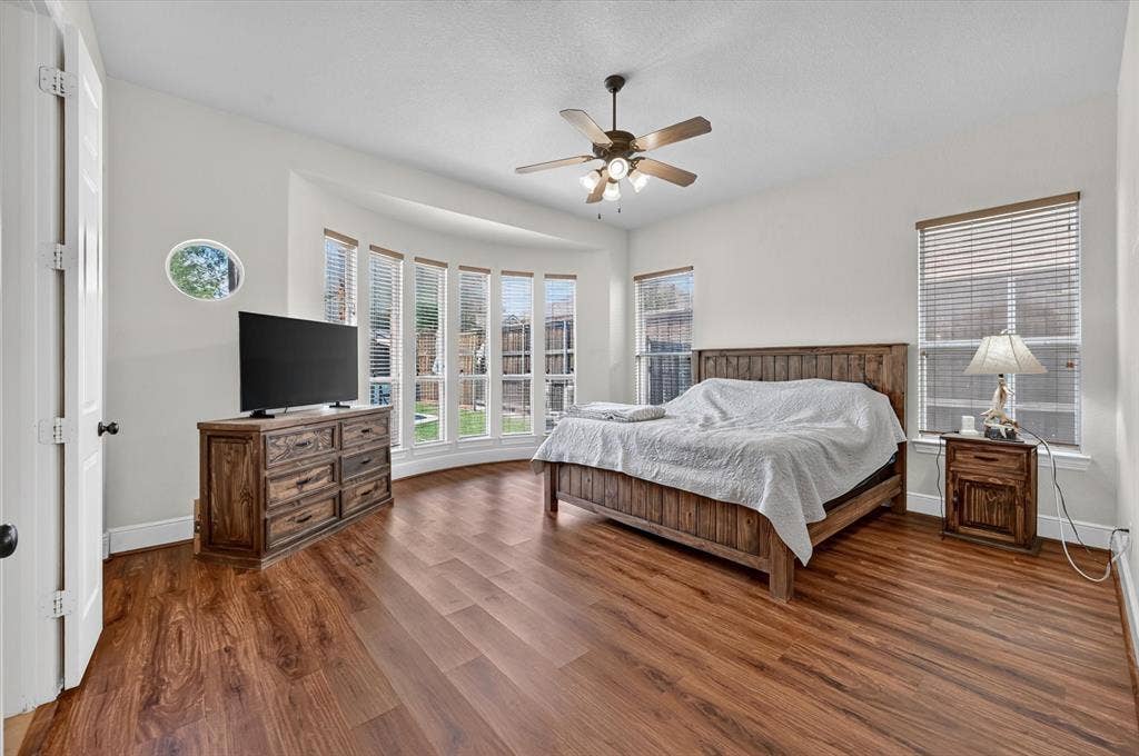 4612 Quiet Circle, Plano, TX 75024 Wood-finish flooring, ceiling fan with integrated lighting, bay window feature, multiple windows with blinds, and a circular accent window