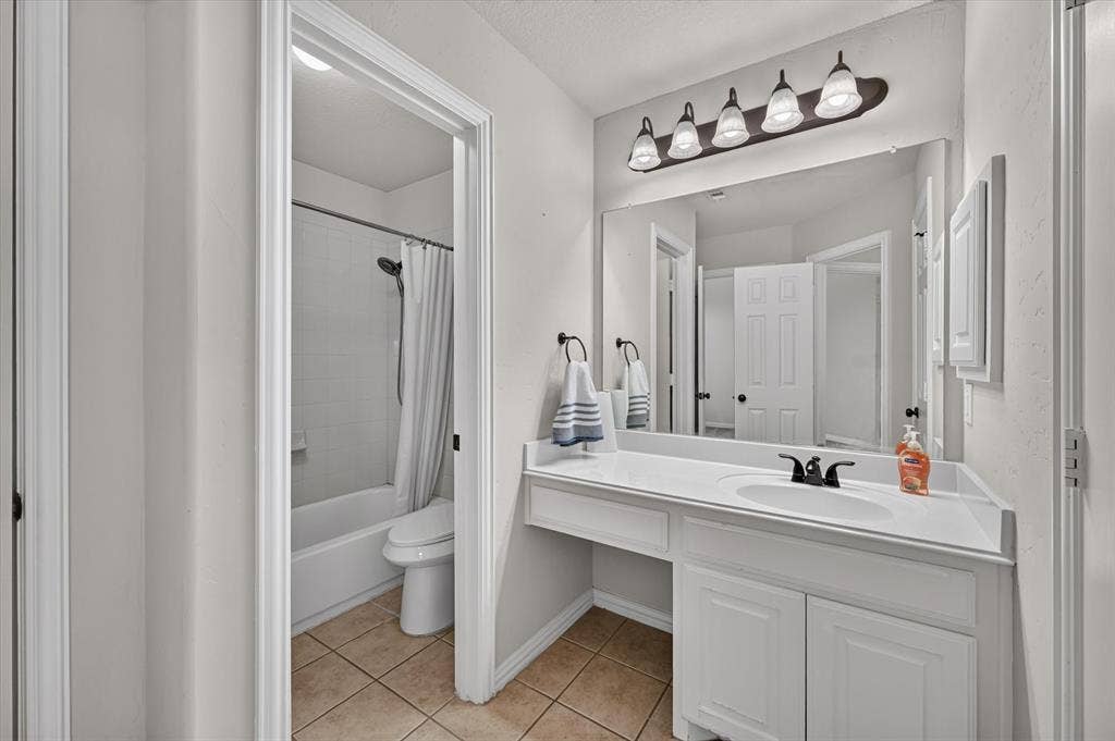 4612 Quiet Circle, Plano, TX 75024 White vanity with an integrated sink and dark-finish faucet, a large wall-mounted mirror, and a five-light fixture