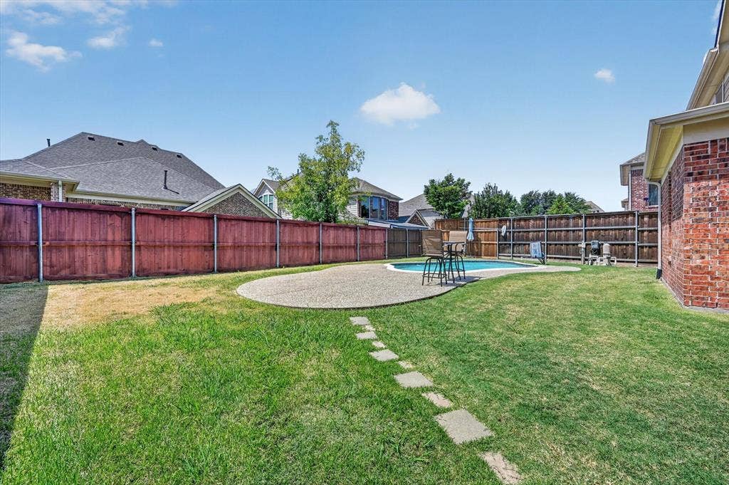 4612 Quiet Circle, Plano, TX 75024 Expansive backyard featuring a swimming pool with an adjacent patio, a stepping stone pathway, and privacy fencing