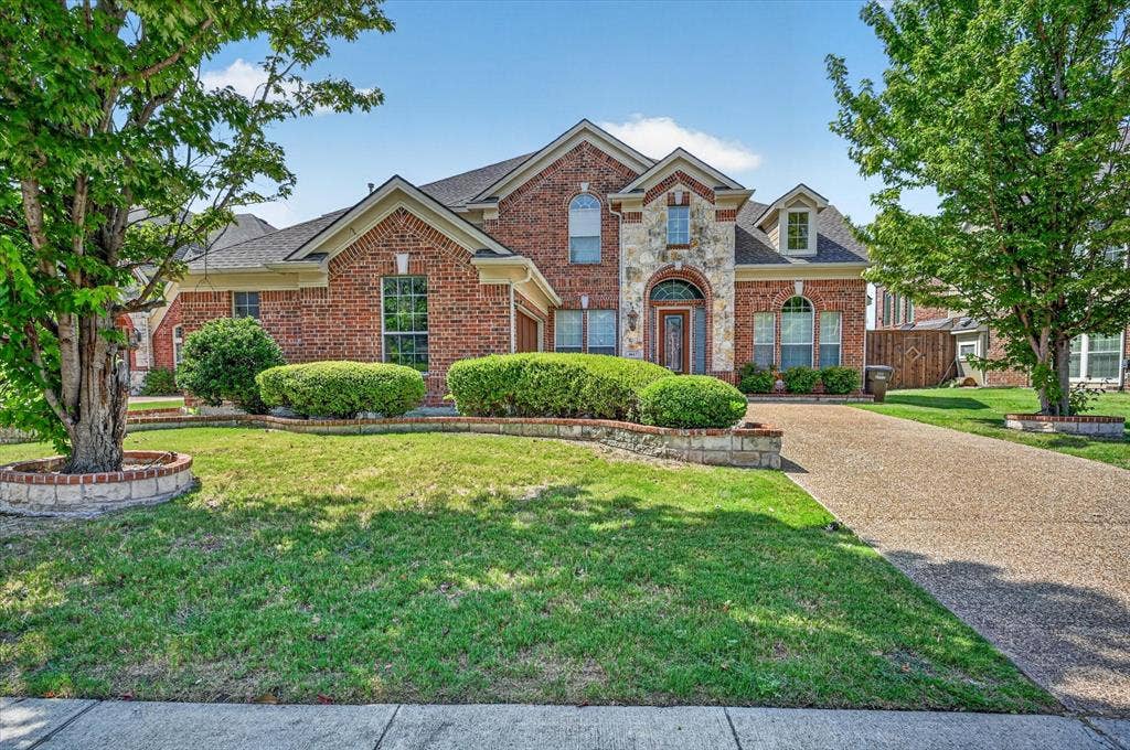 4612 Quiet Circle, Plano, TX 75024 Brick and stone exterior with arched windows, gabled rooflines, and a paved driveway