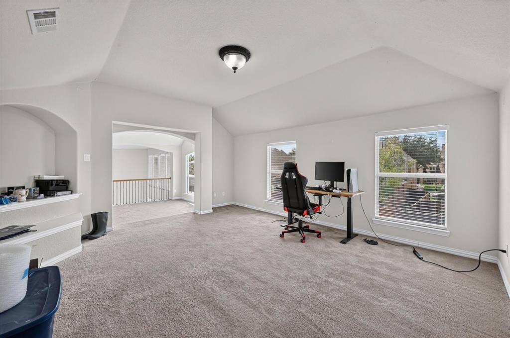 4612 Quiet Circle, Plano, TX 75024 Carpeted room featuring multiple windows with blinds, an arched doorway, and an integrated ceiling light fixture
