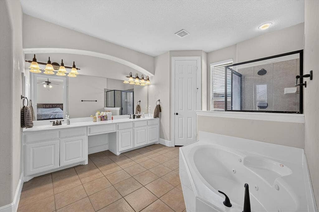 4612 Quiet Circle, Plano, TX 75024 Dual vanity with white cabinetry, built-in makeup vanity, large wall-mounted mirror, and tile flooring