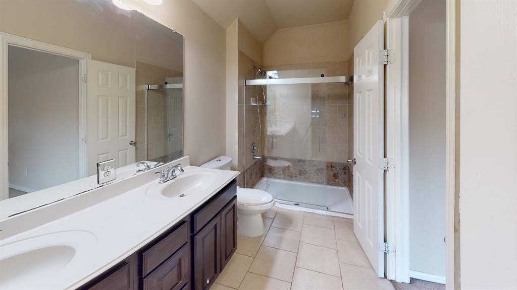 4651 Penelope Lane, Plano, TX 75024 Double vanity with integrated sinks, full-width mirror, and dark wood-finish cabinetry