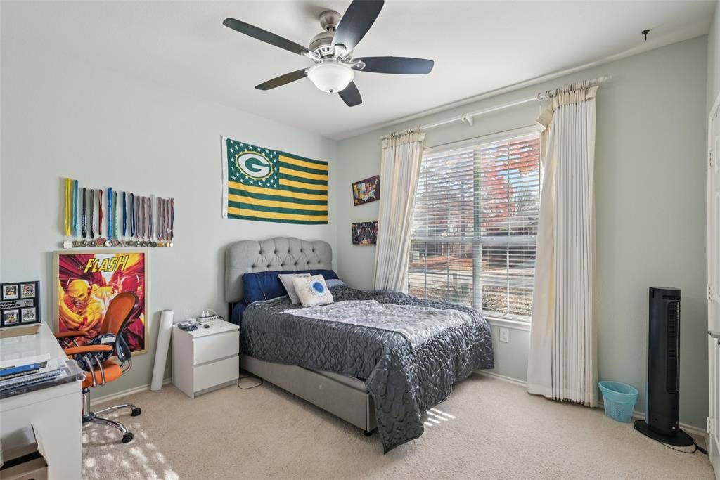 Plush carpet flooring, a window with blinds, and a ceiling fan with integrated lighting