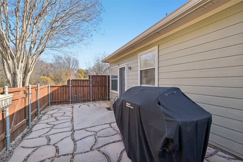 Patio featuring irregular flagstone pavers, wooden privacy fencing, and exterior siding