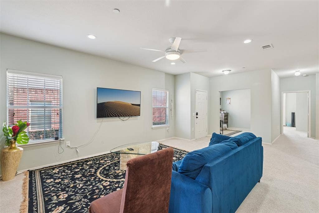 Recessed lighting, ceiling fan with integrated light, multiple windows with blinds, light-toned carpeting, and a white interior door