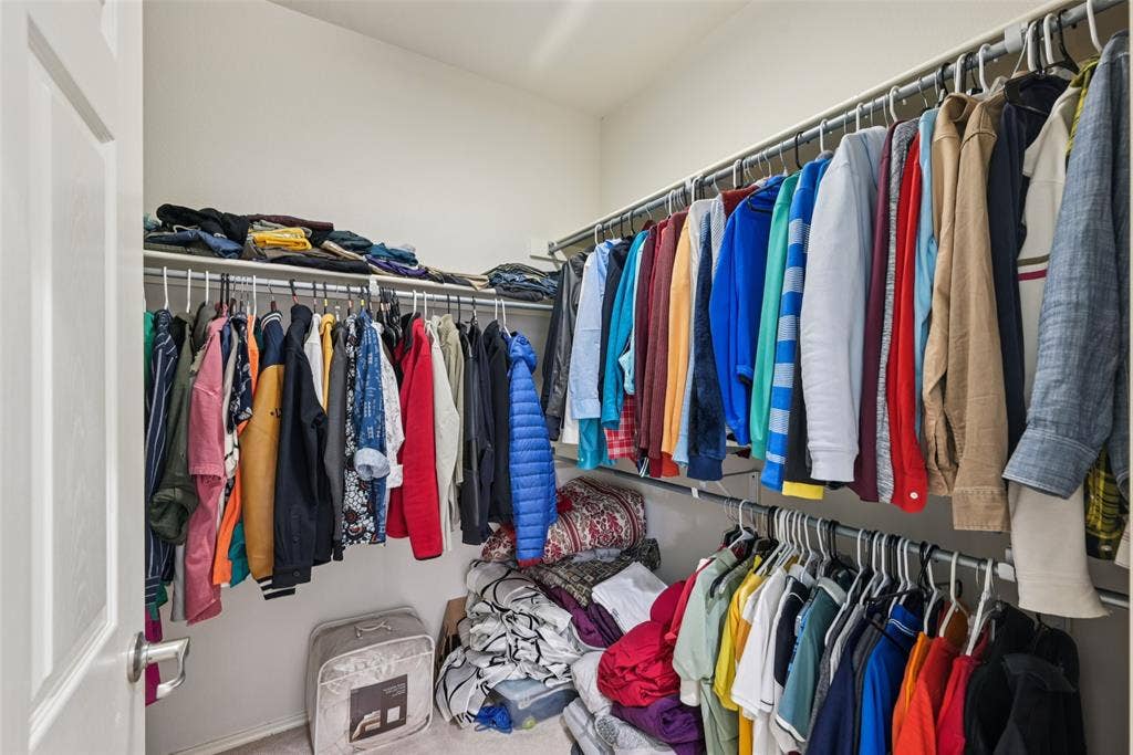 Walk-in closet featuring built-in shelving, multiple hanging rods, and neutral-toned carpeting