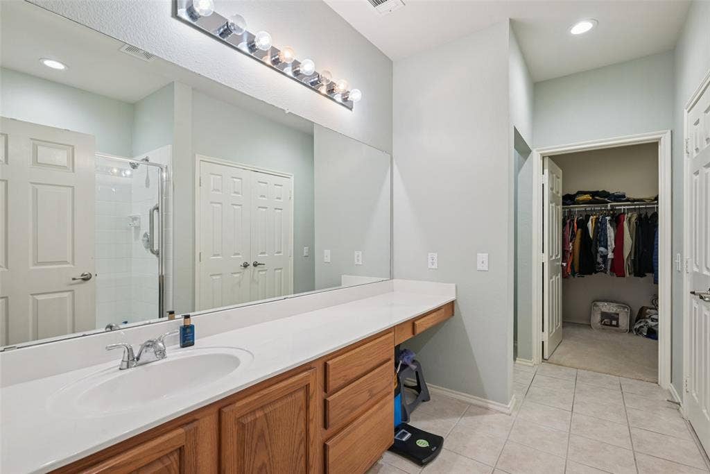 Extended vanity with a built-in sink, wood-finish cabinetry, and a full-width mirror with overhead lighting