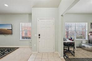 Entryway with tile flooring, a paneled door, and two windows with blinds