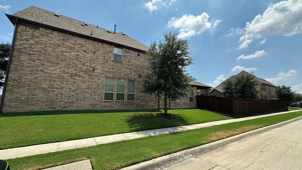 Brick exterior with multiple windows and a shingle roof
