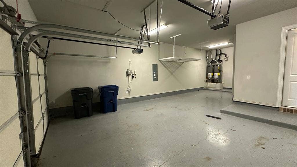 Spacious garage with epoxy-coated flooring, overhead storage racks, and two water heaters